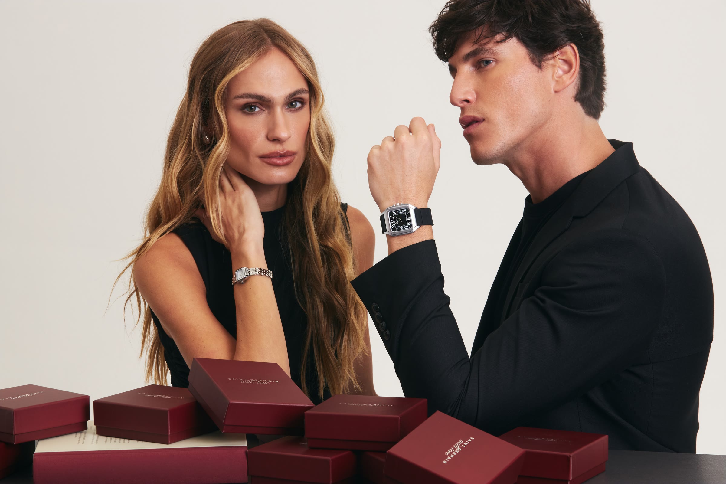 Casal de modelos com relógios Saint Germain e caixas de presente bordô